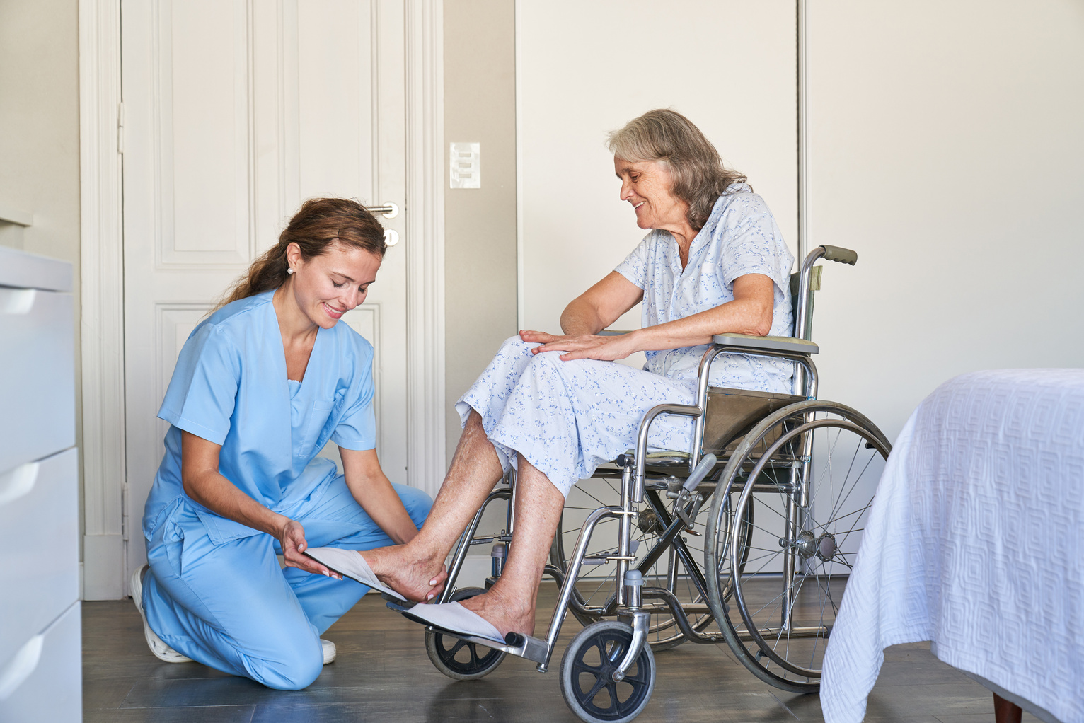 Elderly Care Worker Helps Senior Citizen in a Wheelchair to Put